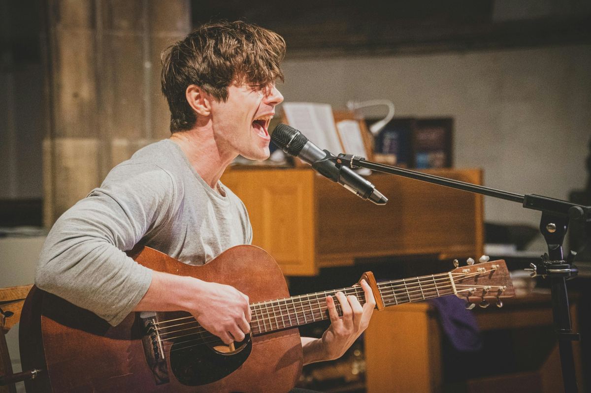 Singer-songwriter performing with an acoustic guitar at a Grab the Mic Session
