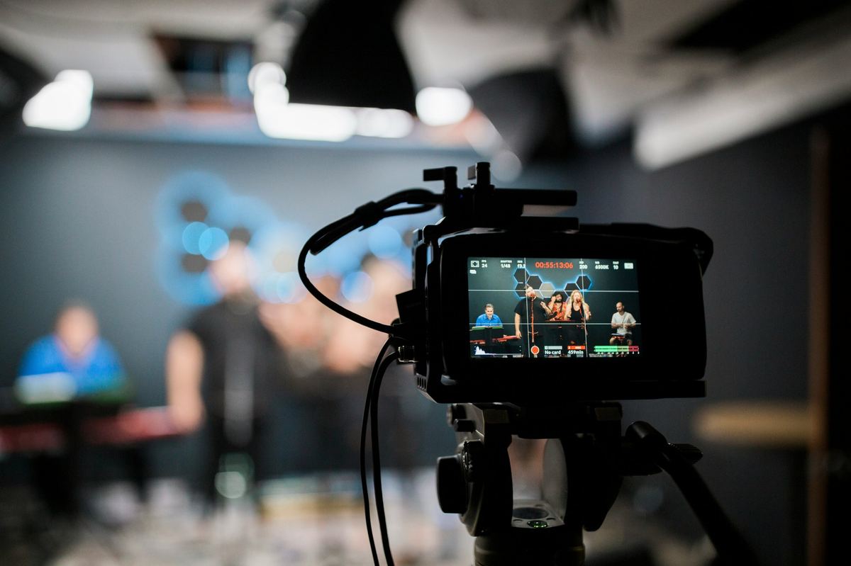 Video camera on a tripod filming a live band for a live stream